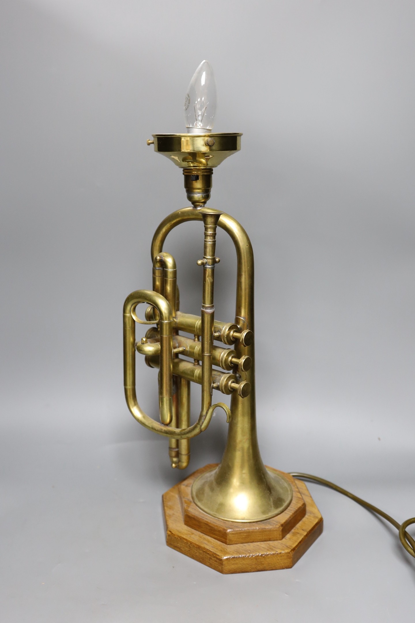 A novelty brass trumpet table lamp and three sconce brass candelabra, trumpet lamp 44cms high including fitting